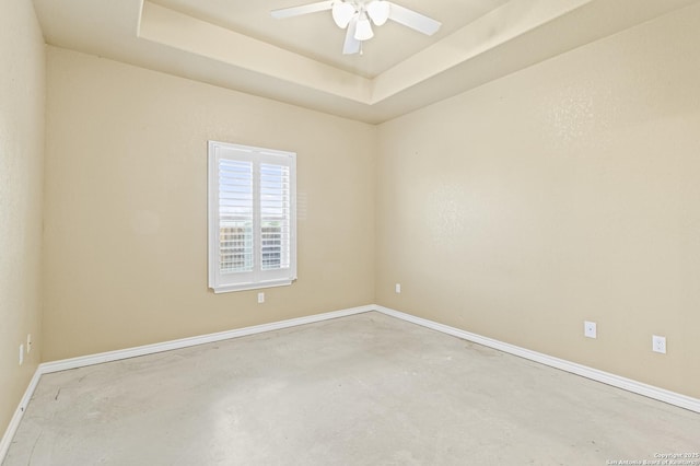 unfurnished room with baseboards, a raised ceiling, ceiling fan, and unfinished concrete floors