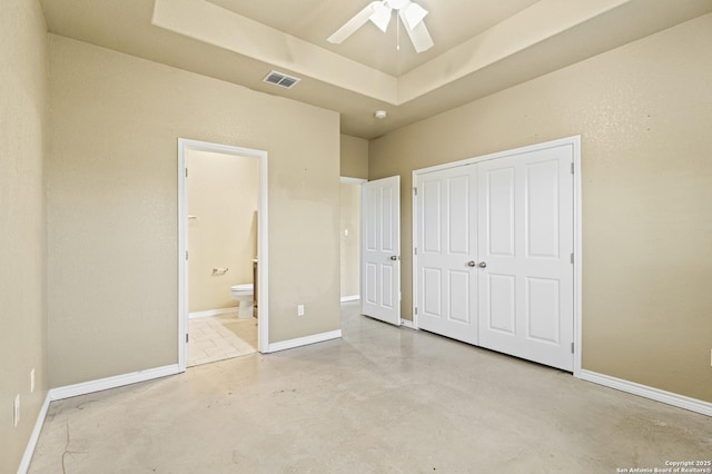 unfurnished bedroom featuring connected bathroom, concrete floors, a closet, visible vents, and a raised ceiling
