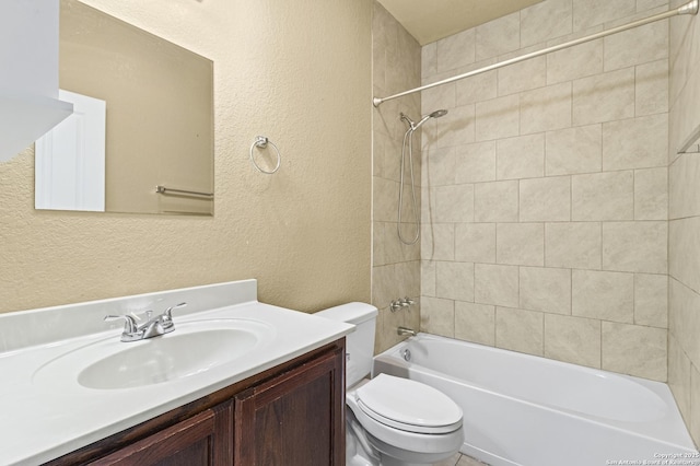 bathroom featuring a textured wall, bathing tub / shower combination, vanity, and toilet