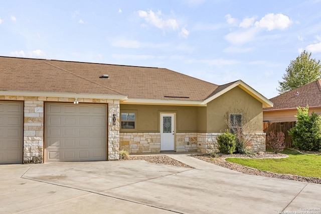 ranch-style home featuring concrete driveway, stucco siding, stone siding, an attached garage, and fence