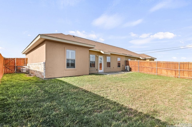 rear view of house with a fenced backyard, stucco siding, a patio area, and a lawn
