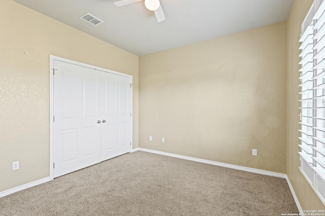 unfurnished bedroom with visible vents, baseboards, a closet, a ceiling fan, and carpet flooring