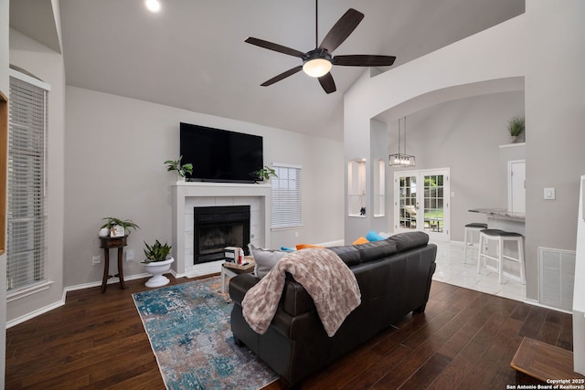 7507 Silent Cloud, San Antonio, TX 78250 - living area featuring ceiling fan, dark wood-style flooring, a tiled fireplace, arched walkways, and high vaulted ceiling