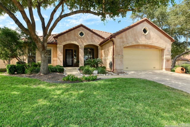 mediterranean / spanish home featuring concrete driveway, a front lawn, stucco siding, and an attached garage