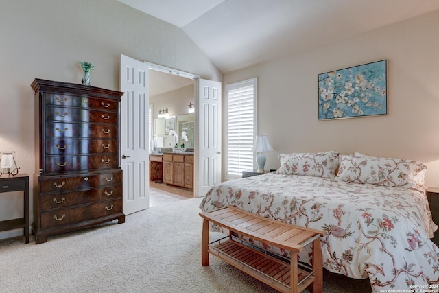 bedroom with ensuite bath, light colored carpet, and vaulted ceiling