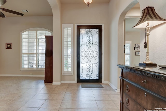 entrance foyer featuring visible vents, baseboards, arched walkways, a ceiling fan, and light tile patterned flooring