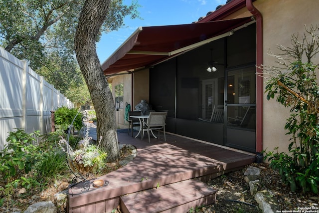 exterior space with outdoor dining space, fence, a sunroom, and stucco siding