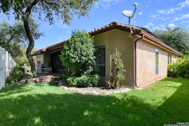 view of side of property featuring fence, a patio, a lawn, and stucco siding