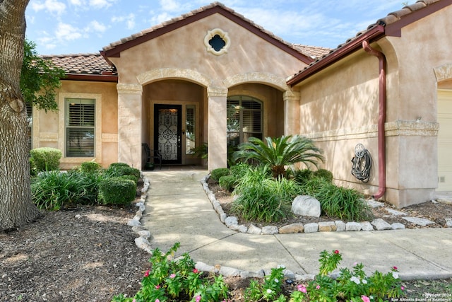 view of exterior entry with a tiled roof and stucco siding
