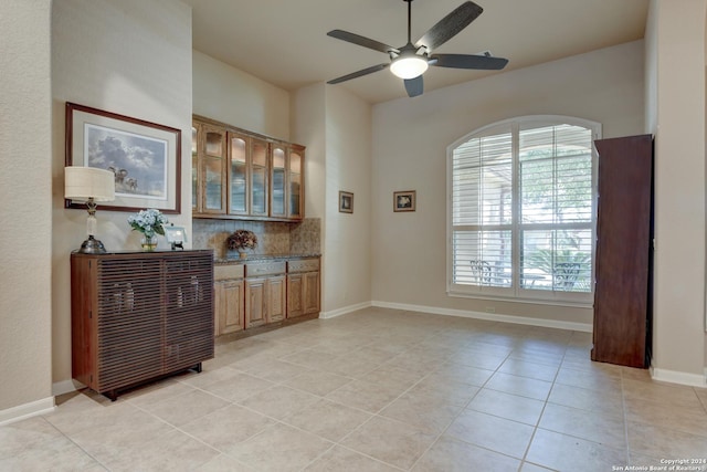 interior space featuring a wealth of natural light, baseboards, light tile patterned flooring, and ceiling fan