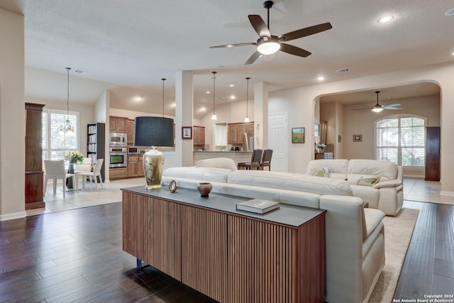 living room with arched walkways, plenty of natural light, visible vents, and ceiling fan