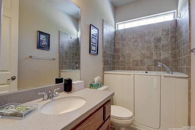 full bath with a textured wall, vanity, a bath, and toilet