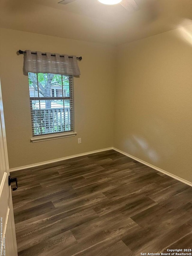 unfurnished room with dark wood-type flooring and baseboards