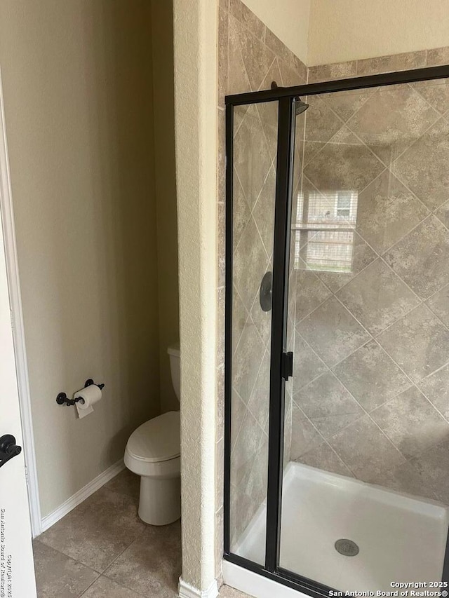 bathroom featuring tile patterned floors, toilet, and a shower stall