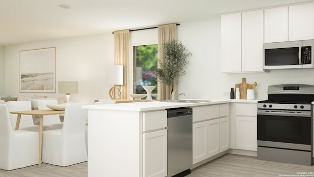kitchen featuring a sink, appliances with stainless steel finishes, a peninsula, and light wood finished floors