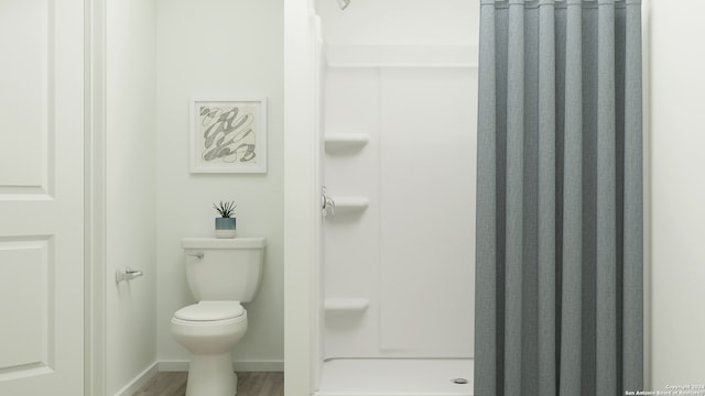 full bath featuring toilet, a stall shower, wood finished floors, and baseboards