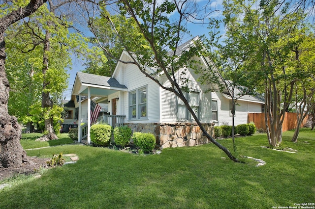 636 W Hollywood Ave, San Antonio, TX 78212 - view of side of home featuring fence, stone siding, and a lawn