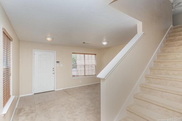 foyer featuring stairs, baseboards, a textured ceiling, and carpet floors