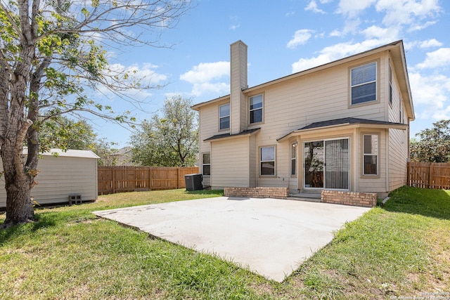 rear view of house featuring entry steps, an outdoor structure, a patio, and a lawn