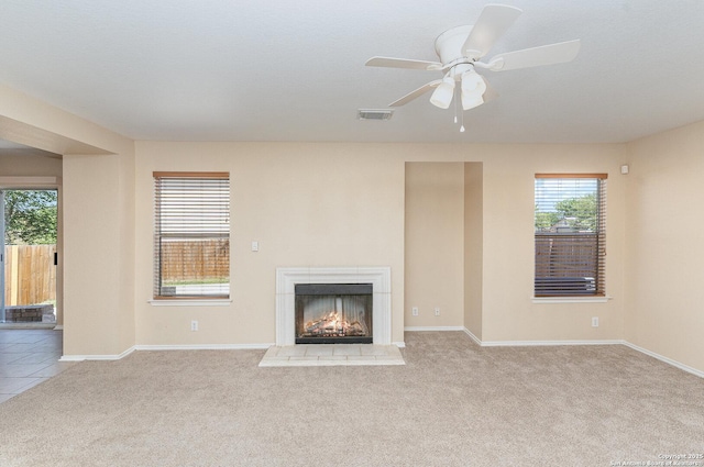 unfurnished living room featuring carpet flooring, visible vents, baseboards, and a warm lit fireplace