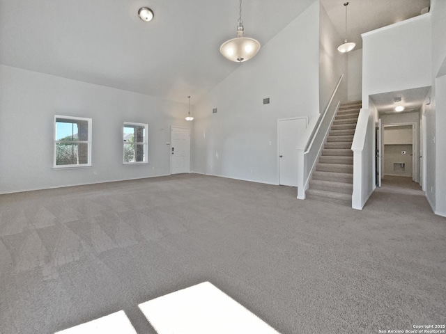 unfurnished living room featuring visible vents, high vaulted ceiling, light colored carpet, and stairs