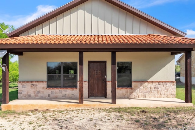723 Tierra Linda, Concan, TX 78838 - rear view of house with board and batten siding, stone siding, and a tile roof