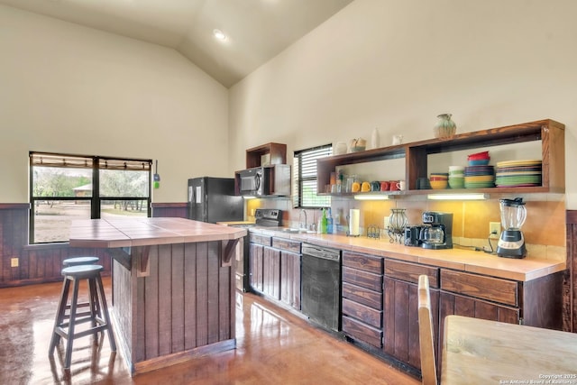 723 Tierra Linda, Concan, TX 78838 - kitchen with high vaulted ceiling, freestanding refrigerator, dishwashing machine, range with electric cooktop, and tile counters