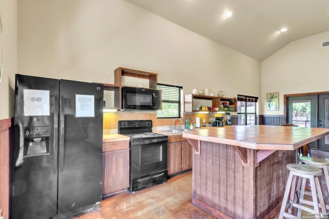 723 Tierra Linda, Concan, TX 78838 - kitchen with tile countertops, high vaulted ceiling, a kitchen breakfast bar, open shelves, and black appliances