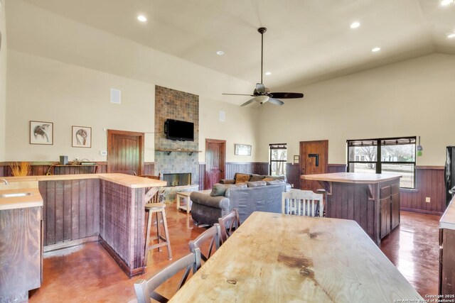 723 Tierra Linda, Concan, TX 78838 - dining area featuring high vaulted ceiling, ceiling fan, recessed lighting, wainscoting, and a brick fireplace