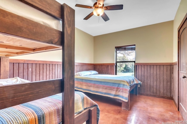 723 Tierra Linda, Concan, TX 78838 - bedroom with wooden walls, wainscoting, ceiling fan, and finished concrete flooring