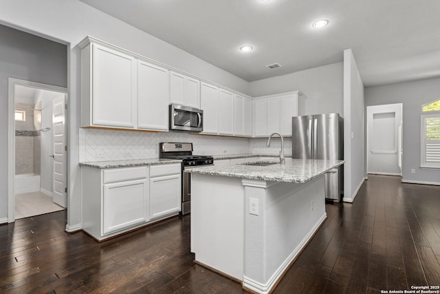kitchen with visible vents, a sink, white cabinetry, light stone countertops, and stainless steel appliances