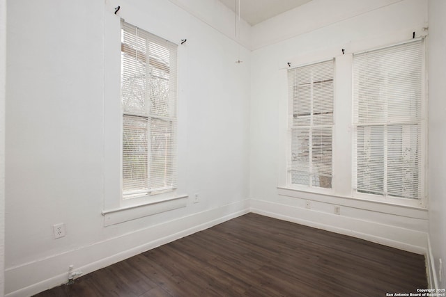 empty room featuring dark wood-style flooring and baseboards