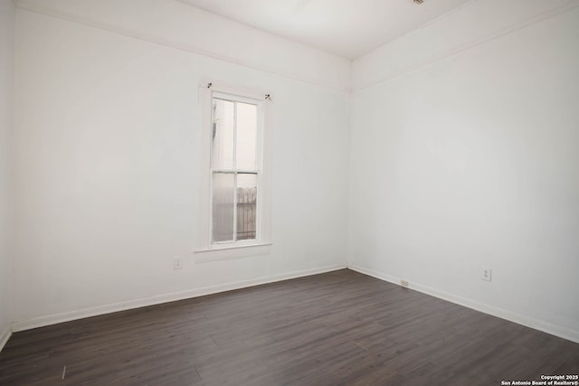 empty room featuring baseboards and dark wood finished floors