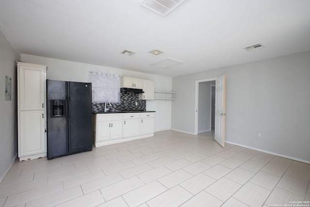kitchen with under cabinet range hood, visible vents, backsplash, and black fridge with ice dispenser
