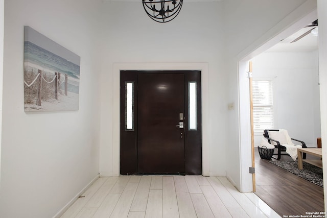 foyer entrance featuring baseboards, a ceiling fan, and wood finished floors