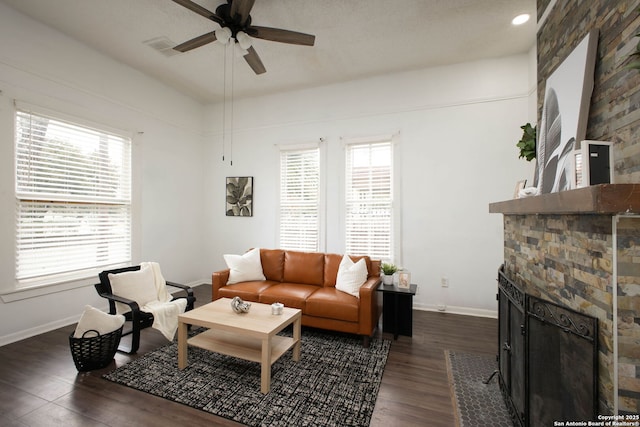 living area featuring a fireplace, dark wood-style flooring, baseboards, and ceiling fan