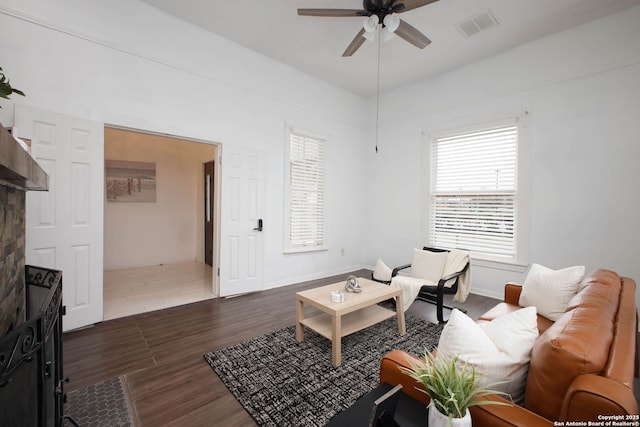 living area featuring dark wood-type flooring, visible vents, and a ceiling fan