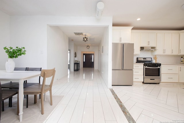 kitchen with range hood, white cabinetry, visible vents, light countertops, and stainless steel appliances