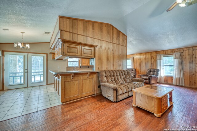 21440 Fm 306, Canyon Lake, TX 78133 - living room with visible vents, a textured ceiling, wooden walls, french doors, and light wood-style flooring