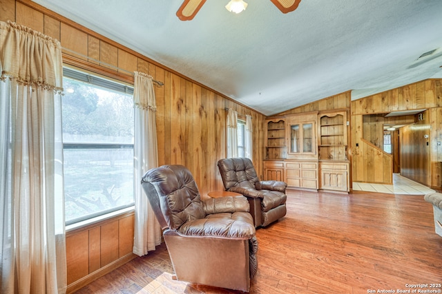 21440 Fm 306, Canyon Lake, TX 78133 - living area featuring light wood-style floors, wood walls, a ceiling fan, and lofted ceiling
