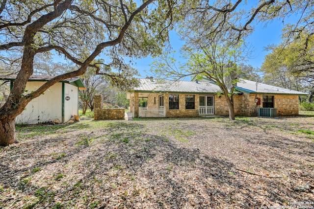 21440 Fm 306, Canyon Lake, TX 78133 - back of property featuring an outbuilding, metal roof, stone siding, and central AC unit