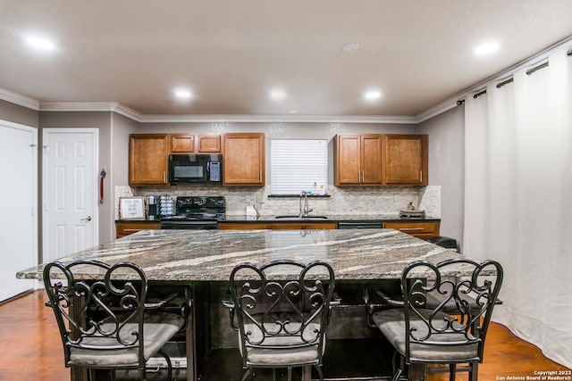 2230 Bedford Stage, San Antonio, TX 78213 - kitchen with a large island, a sink, a kitchen bar, brown cabinetry, and black appliances
