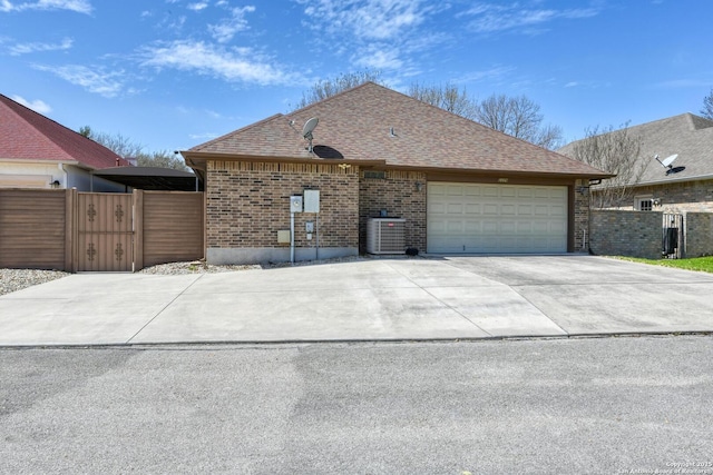 2239 Kensington Way, New Braunfels, TX 78130 - view of side of property with central AC, an attached garage, concrete driveway, brick siding, and a gate