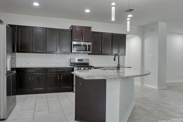 8732 Ironwood Hl, San Antonio, TX 78254 - kitchen featuring backsplash, appliances with stainless steel finishes, arched walkways, a sink, and light tile patterned floors