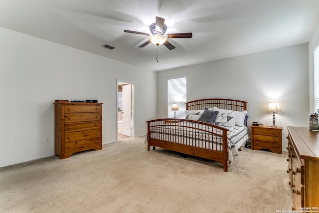 bedroom with light colored carpet, a ceiling fan, baseboards, ensuite bathroom, and visible vents