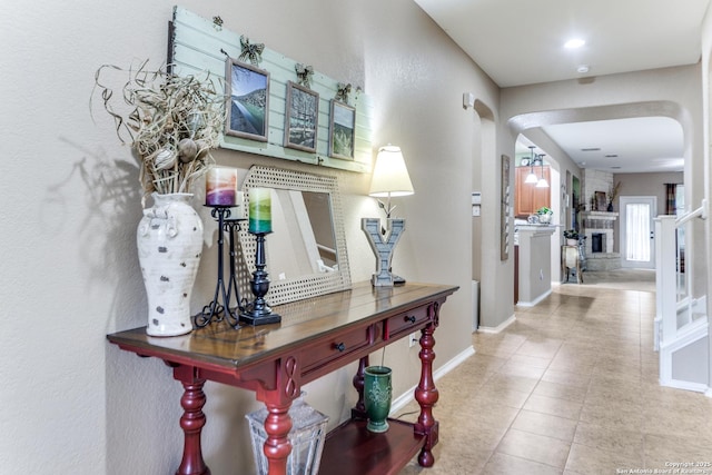 hallway featuring arched walkways, baseboards, and tile patterned flooring
