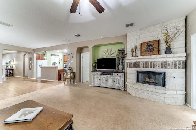 living area with visible vents, ceiling fan, and a fireplace