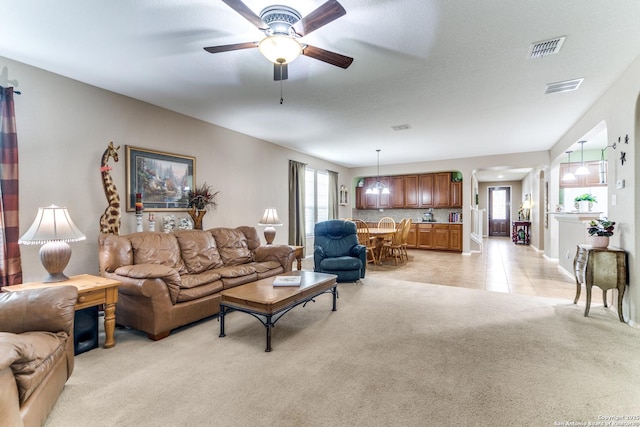 living area with ceiling fan, light colored carpet, and visible vents