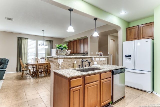 kitchen with a sink, white fridge with ice dispenser, tasteful backsplash, stainless steel dishwasher, and visible vents