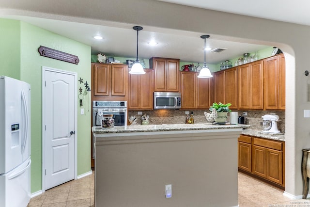 kitchen featuring brown cabinetry, tasteful backsplash, light tile patterned floors, decorative light fixtures, and stainless steel appliances